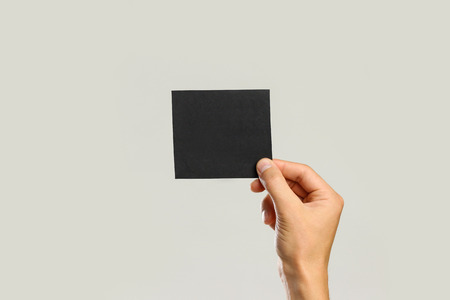Male hands holding a black sheet of paper. Isolated on gray background. Closeup.の写真素材