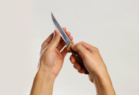 Male hands holding a sharp kitchen knife with a wooden handle. Isolated on gray background. Closeup.