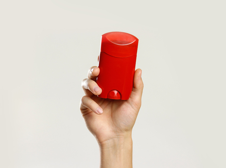 Male hands holding red deodorant. Isolated on gray background. Closeup.の写真素材