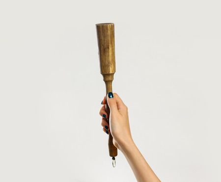 Female hands holding a wooden pestle. Isolated on gray background. Closeup.