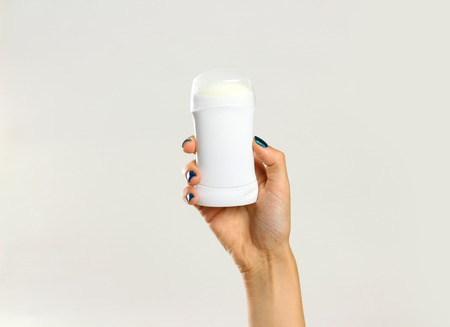 Female hands holding white deodorant. Isolated on gray background. Closeup.
