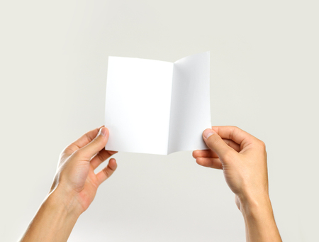 Male hands holding a white sheet of paper. Isolated on gray background. Closeup.の写真素材