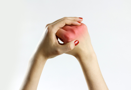 The girl has a pain in his hand. Holding his hands behind his hand. Closeup.の写真素材