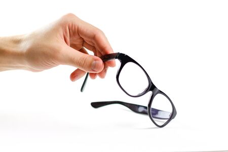 Hand holds transparent glasses for correction of sight. Isolated on white background.の写真素材