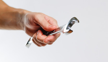 Hand holds open-end wrench. Tool kit for the car. Isolated on white background.の写真素材