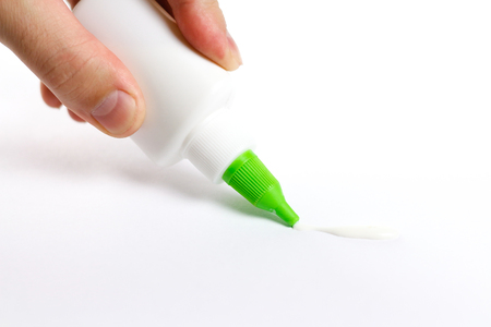 Hand holding a bottle of glue. Deals PVA glue on paper. Isolated on white background.の写真素材