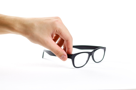 Hand holds transparent glasses for correction of sight. Isolated on white background.の写真素材