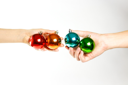 Hands holding Christmas ball. On the background of many Christmas balls. Lot Christmas tree decorations. Colored glass balls. Isolated on a white background.の写真素材