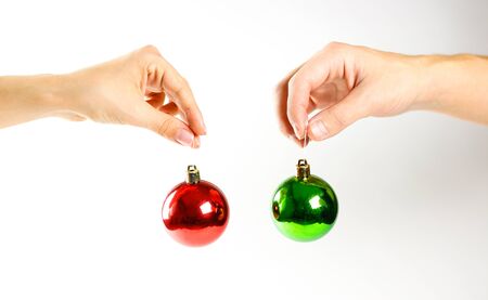 Hands holding Christmas ball. On the background of many Christmas balls. Lot Christmas tree decorations. Colored glass balls. Isolated on a white background.の写真素材