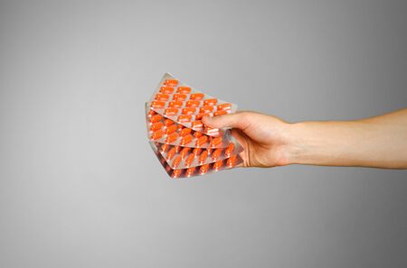 Hand holding a few packets of capsules orange