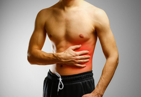 The guy with no shirt holding hand of the patient side. Stomach hurts. Pain in the liver. The location of the pain marked in red.の写真素材