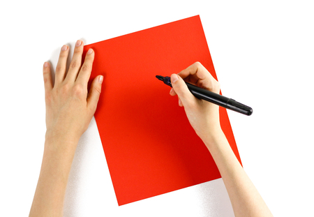 Hand holding black marker on red paper on a white background. Closeup.の写真素材