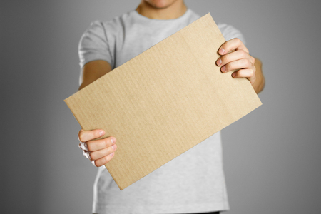 A young guy in a white t-shirt holding a piece of cardboard. Prepared for your text.の写真素材