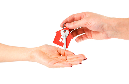 The hand holds the keys with the red house keychain. Purchase of apartments. House in hands. Close up. Isolated on a white background.の写真素材