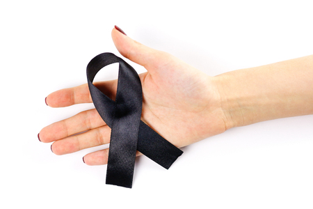 Hand holding black ribbon on a white background. Folded ribbon. Close up.の写真素材