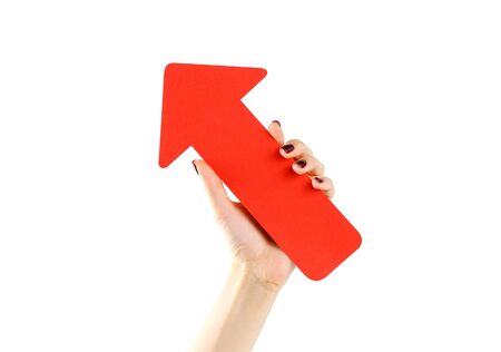 Female hand holding big red arrow. Close up. Isolated on a white background.の写真素材