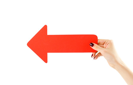 Female hand holding big red arrow. Close up. Isolated on a white background.の写真素材