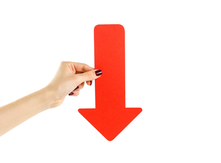 Female hand holding big red arrow. Close up. Isolated on a white background.の写真素材