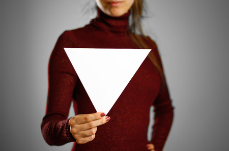 Woman showing blank triangular white paper. Leaflet presentation. Pamphlet hold hands. Girl show clear offset paper. Sheet templateの写真素材