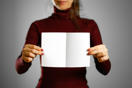 Woman showing blank white flyer paper. Leaflet presentation. Pamphlet hold hands. Girl show clear offset paper. Sheet templateの写真素材