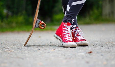 Girl in red sneakers on a skateboard. Feet on a skateboard