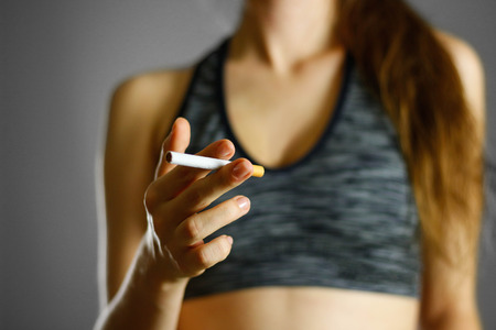 Sports girl holding a cigarette. Close up. Isolated background.