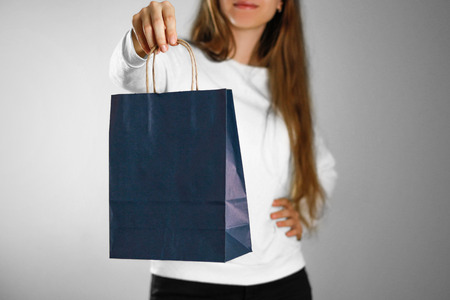 Girl holding a blue gift bag. Close up. Isolated background.