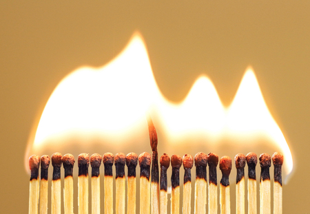 Burning match among others on isolated background. Difference and uniqueness concept.