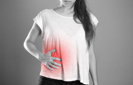 Girl holding her side. Pain in the liver. Syros liver. Close up. Isolated background.の写真素材