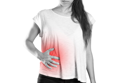 Girl holding her side. Pain in the liver. Syros liver. Close up. Isolated on white background.の写真素材