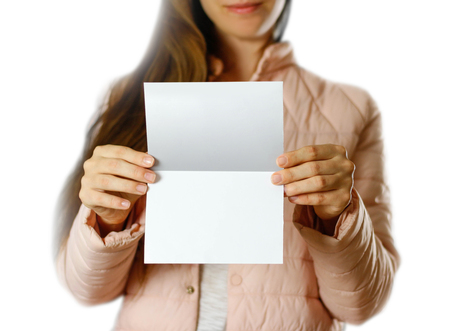 A woman in a warm winter jacket holding a white leaflet. Blank paper. Close up. Isolated on white background.の写真素材