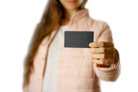A woman in a warm winter jacket holding a black leaflet. Blank paper. Close up. Isolated on white...