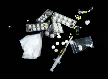 Drugs on a black background. Syringe, needle, pills, white powder, candle, spoon. Close up