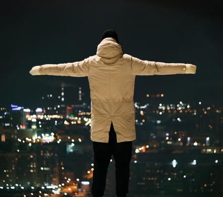 Man with arms outstretched against the night city lights