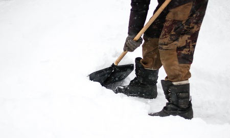 A man cleans snow with a shovel. The dusting of snow. Close up.