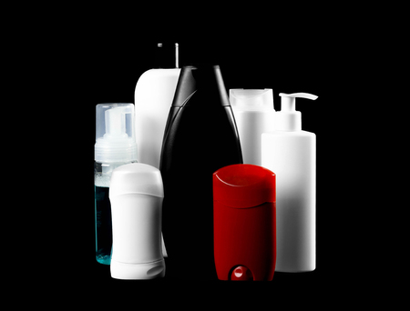 Means for self-care. Bottles of shampoo, antiperspirants. Close up. Isolated on black background.