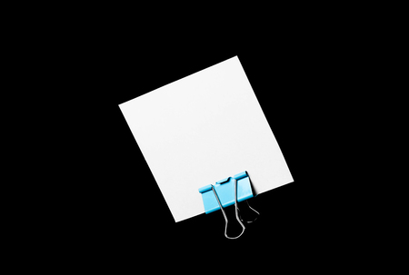 An empty white business card stands on a stationery clip. Close up. Isolated on black background.の写真素材