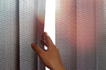 Hand opens black vertical blinds of fabric on the window. Close up.の写真素材