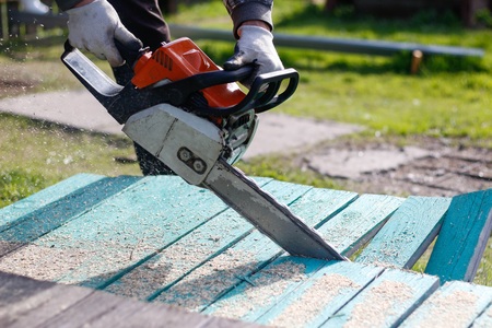 Man sawing boards with a chainsaw. Close up.