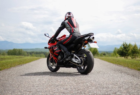KRASNOYARSK, RUSSIA - May 31, 2019: Beautiful motorcyclist in full gear and helmet on a red and black Honda 2005 CBR 600 RR (PC37).のeditorial素材