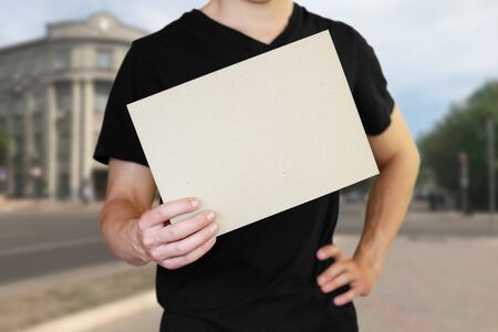 A man holding a white sheet of paper. Holding a booklet. Close up. The background of the city.の写真素材
