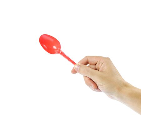 Hand holding plastic red disposable spoon. Close up. Isolated on white background.の写真素材