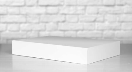 A white laptop box sits on a wooden table. Close up.の写真素材