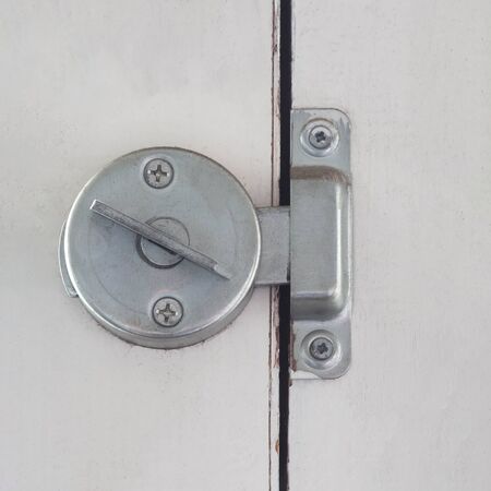 Metallic silver flap on the old window. Close up.