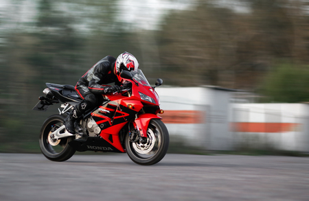 KRASNOYARSK, RUSSIA - August 27, 2019: Beautiful motorcyclist in full gear and helmet on a red and black Honda 2005 CBR 600 RR (PC37).のeditorial素材