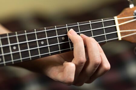Hand holding a chord on the ukulele. Close up. Isolated on white background.