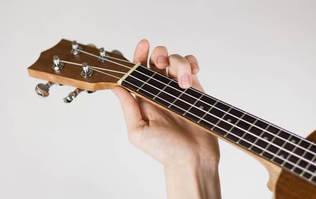 Hand holding a chord on the ukulele. Close up. Isolated on white background.