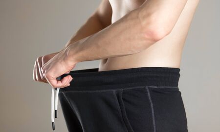 The man looks down his pants. Close up. Isolated on grey background.の写真素材