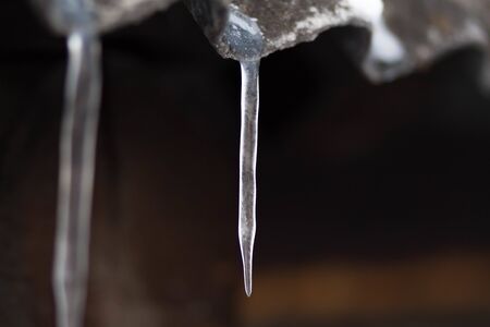 Icicles hang on the old roof. Close up.の写真素材