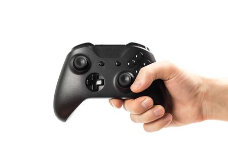 The hand holds a black gamepad for playing computer games. Isolated on a white background. Close up.